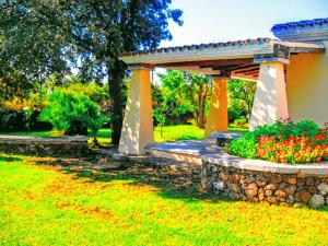 a garden with a stone wall and a pergola at Orosei RE - Villa Osala - 800 m dal mare in Orosei