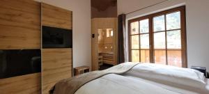 een slaapkamer met een bed en een groot raam bij Hochalmbahnen Chalets Rauris 1-20 WE4, Maislaufeldweg 1r OG in Rauris