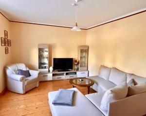 uma sala de estar com dois sofás brancos e uma televisão em Ferienhaus Mühlberg em Radebeul
