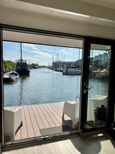 a house with a view of a river with boats at Surla luxury sailing Houseboat Splendid at Marina Monnickendam in Monnickendam