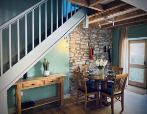ein Esszimmer mit einem Tisch und einer Treppe in der Unterkunft Priestley Cottage in Buxton