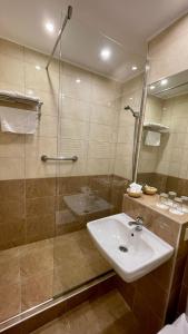 uma casa de banho com um lavatório e uma cabina de duche em vidro. em Hotel Magistern Konferencia és WellnessHotel em Siófok