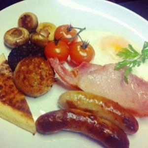a plate of breakfast food with eggs sausage and tomatoes at Westgate House B&B Strokestown in Strokestown