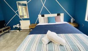a blue bedroom with a bed with two white towels on it at Westminster Mount View Unit 1 in Rotorua