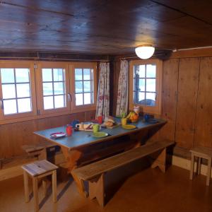 ein Esszimmer mit einem Tisch, Bänken und Fenstern in der Unterkunft Hami in Adelboden