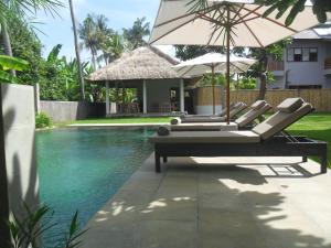 una piscina con sillas y una sombrilla junto a una casa en Ju'Blu Hotel, en Lovina