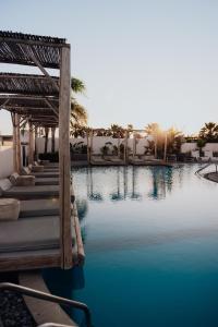 una piscina en un complejo con agua azul y palmeras en Casa Cabana Boutique Hotel & Spa - Adults Only en Faliraki
