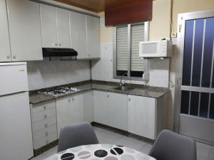 una cocina con armarios blancos y una mesa con sillas. en Apartamento con terraza y vistas al mar, en Bueu