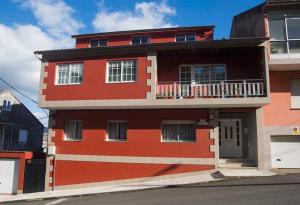 un edificio rojo con un balcón en el lateral. en Apartamento con terraza y vistas al mar, en Bueu
