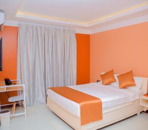 a bedroom with orange walls and a bed and a desk at Hotel Amaranth in Dar es Salaam