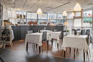 um restaurante com mesas e cadeiras brancas e uma cozinha em Sure Hotel by Best Western Focus em Örnsköldsvik