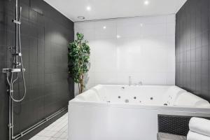 a white bathroom with a tub and a plant at Sure Hotel by Best Western Focus in Örnsköldsvik