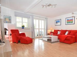 uma sala de estar com um sofá vermelho e duas cadeiras em Villa Freya - Apt. 06 em Ostseebad Sellin