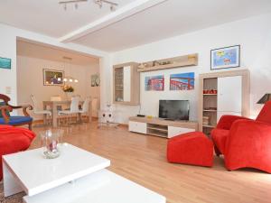 uma sala de estar com cadeiras vermelhas e uma televisão em Villa Freya - Apt. 06 em Ostseebad Sellin