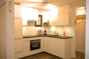 a kitchen with white cabinets and a sink at CAYA Bijou im Herzen von Zermatt in Zermatt