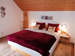 ein Schlafzimmer mit einem großen Bett mit roter Bettwäsche und Kissen in der Unterkunft B&B Haus Holunder Weissbriach in Weissbriach