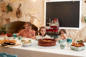 una donna e due bambini seduti a un tavolo con del cibo di Dei Serafini a Polignano a Mare