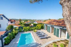 uma vista sobre uma piscina com cadeiras e uma casa em Maison d'hôtes Etxea_&_co em Bidart