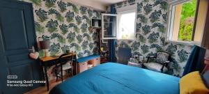 a bedroom with a blue bed and a desk at Chambres d'hôtes Les Chênes in Acigné