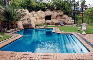 uma piscina num quintal com uma parede de pedra em Gold Reef City Theme Park Hotel em Joanesburgo