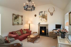 a living room with a red couch and a fireplace at Riverside Cottage, Bridge of Balgie, Glenlyon, Perthshire 