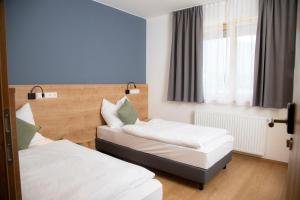 2 Betten in einem kleinen Zimmer mit Fenster in der Unterkunft Sporthotel Ferlach in Ferlach