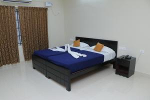 a bedroom with a bed with blue sheets and white towels at Hotel TamilNadu -Trichy in Tiruchirappalli