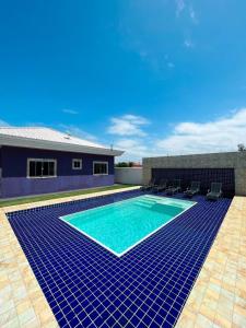 ein Pool mit blauen Fliesen vor einem Haus in der Unterkunft casa de praia com piscina e hidromassagem in Arraial do Cabo