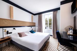 ラ・フロットにあるHôtel Le Françaisの大きなベッドとデスクが備わるホテルルームです。