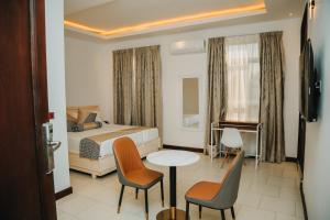 a hotel room with a bed and a table and chairs at Hotel Amaranth in Dar es Salaam