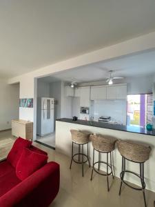ein Wohnzimmer mit einem roten Sofa und einer Küche in der Unterkunft casa de praia com piscina e hidromassagem in Arraial do Cabo