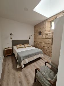 a bedroom with a bed and a stone wall at Pensión A Xanela in Pontevedra