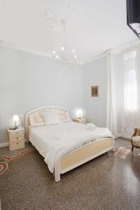 a white bedroom with a large bed and a chandelier at B&B Elisir in Albenga