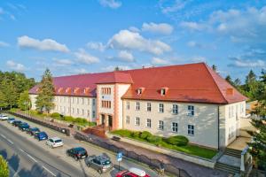 a large building with a red roof on a street at Rewita Rogowo k Kołobrzegu in Rogowo