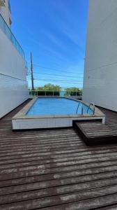 una piscina en un edificio con terraza de madera en Apartamento peracanga com vista para o mar en Guarapari