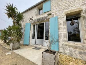 una casa de ladrillo con puertas azules y una palmera en Maison Dompierre-sur-Mer, 2 pièces, 4 personnes - FR-1-246-603, en Dompierre-sur-Mer