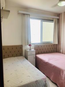 a bedroom with two beds and a window at Apartamento peracanga com vista para o mar in Guarapari +40 photos