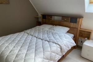 Schlafzimmer mit einem weißen Bett mit einem Kopfteil aus Holz in der Unterkunft Maison de vacances à Gramat in Gramat