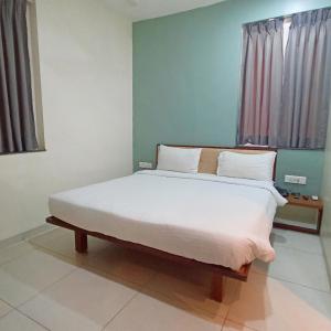 een slaapkamer met een groot bed met witte lakens bij Sharman Suites in Pune