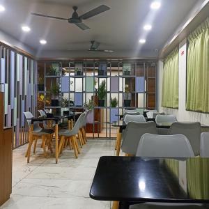 a restaurant with tables and chairs and a ceiling fan at Sharman Suites in Pune