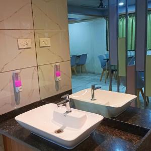 a bathroom with two sinks and a mirror at Sharman Suites in Pune