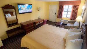 a hotel room with a bedroom with a bed and a desk at Loyalty Inn Hawkinsville in Hawkinsville