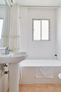 Apartamentos San Antonio Beach في خليج سان أنتوني: حمام أبيض مع حوض وحوض استحمام