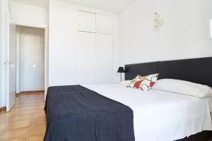 a bedroom with a large white bed with a black headboard at Apartamentos San Antonio Beach in San Antonio Bay