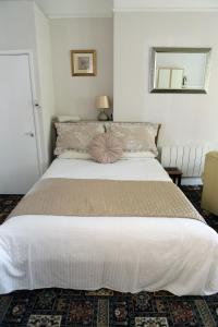 a bedroom with a large white bed with a mirror at Abbey View Holiday Flats in Torquay
