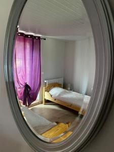 a mirror reflecting a bedroom with a bed and a purple curtain at Gîte à Rocamadour in Rocamadour