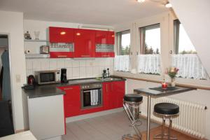 una cucina con armadi rossi e ripiani neri di Diamanthaus 2 Koblenz a Coblenza