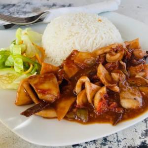 a plate of food with rice and meat and vegetables at Mwananchi Bungalows in Paje