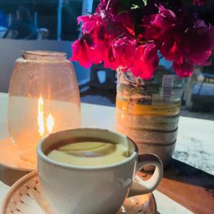 a cup of coffee on a plate next to a vase with flowers at Mwananchi Bungalows in Paje