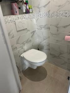 baño con azulejos de mármol y aseo blanco en Magnifique appartement de 60m2, en Le Blanc-Mesnil